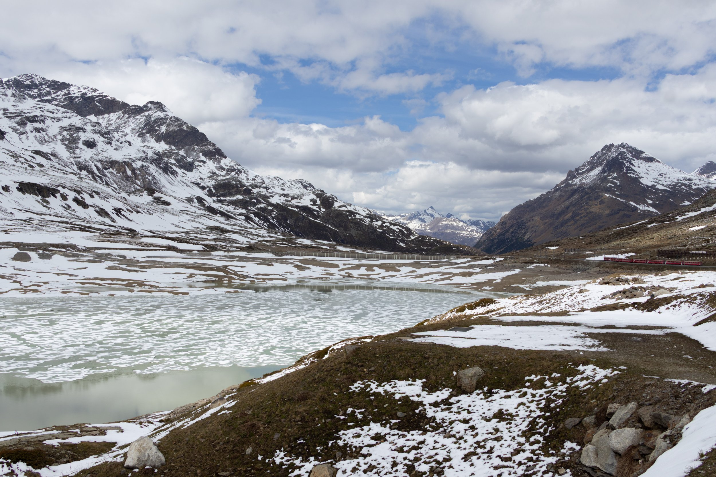 Lago Bianco, Switzerland | A partially frozen lake surrounded by the snow-covered Swiss alps. 