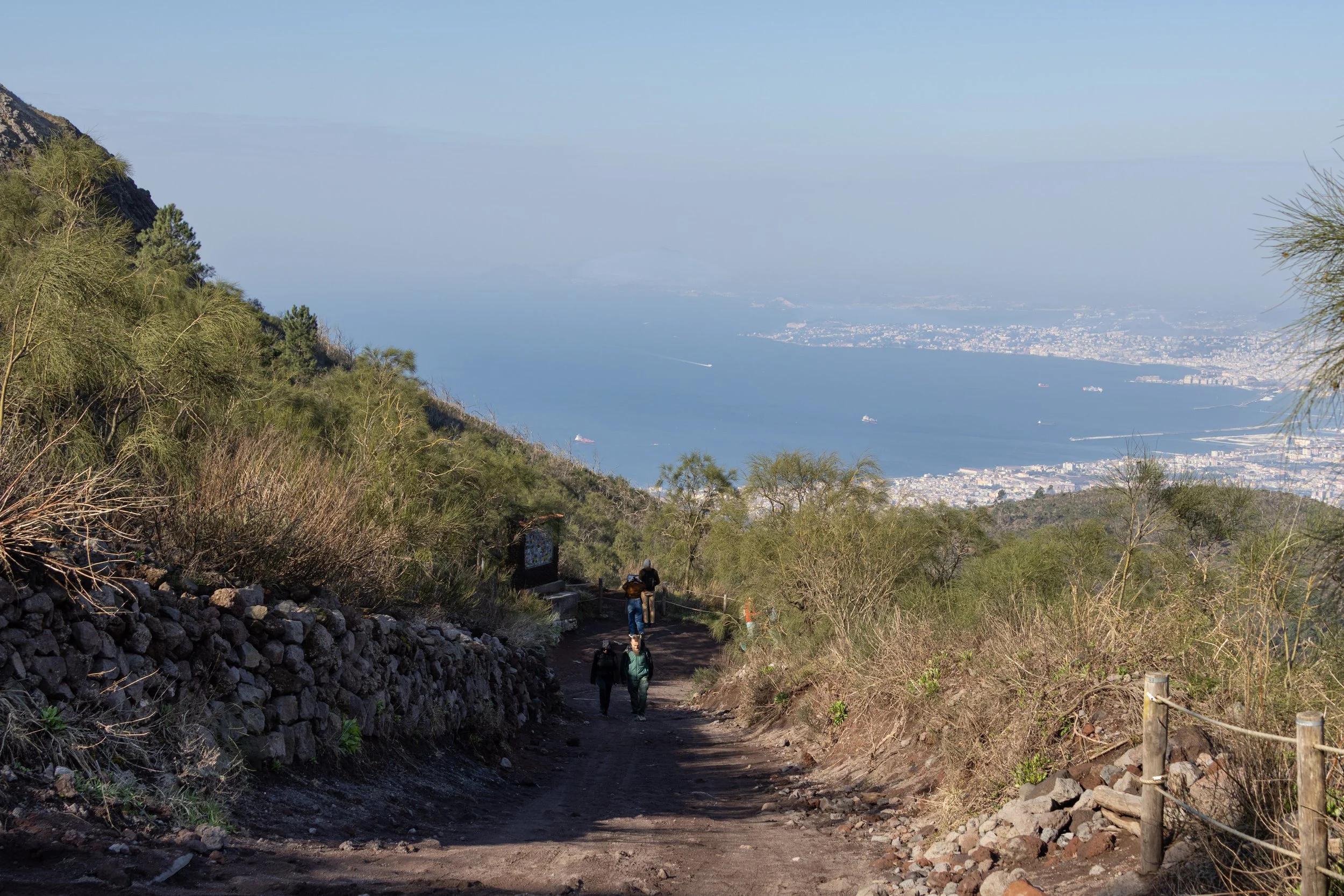 Naples, Italy | A trail descending the slopes of Mount Vesuvius, with the Bay of Naples in the distance. 
