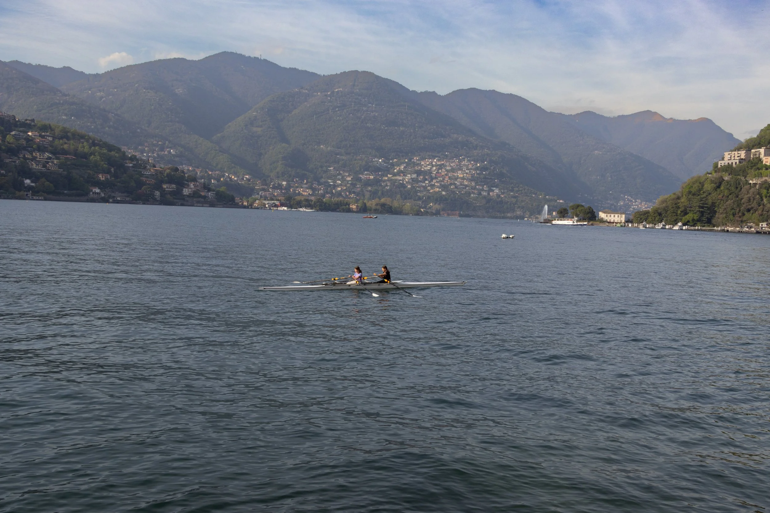 Lake Como, Italy | Rowers cross the calm waters of Lake Como beneath the surrounding mountain landscape.