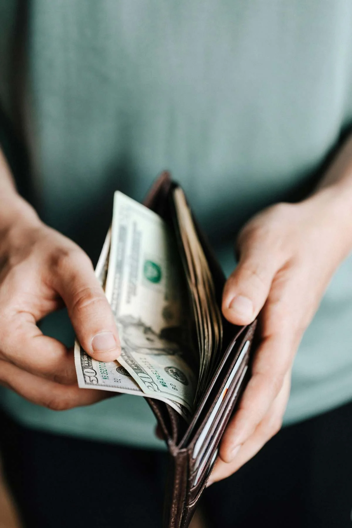 Image of man opening up his wallet with cash.