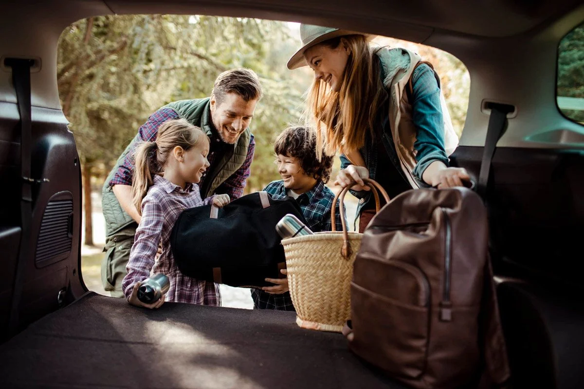 Auto Loan: Parents and two kids smiling while unloading the back of car