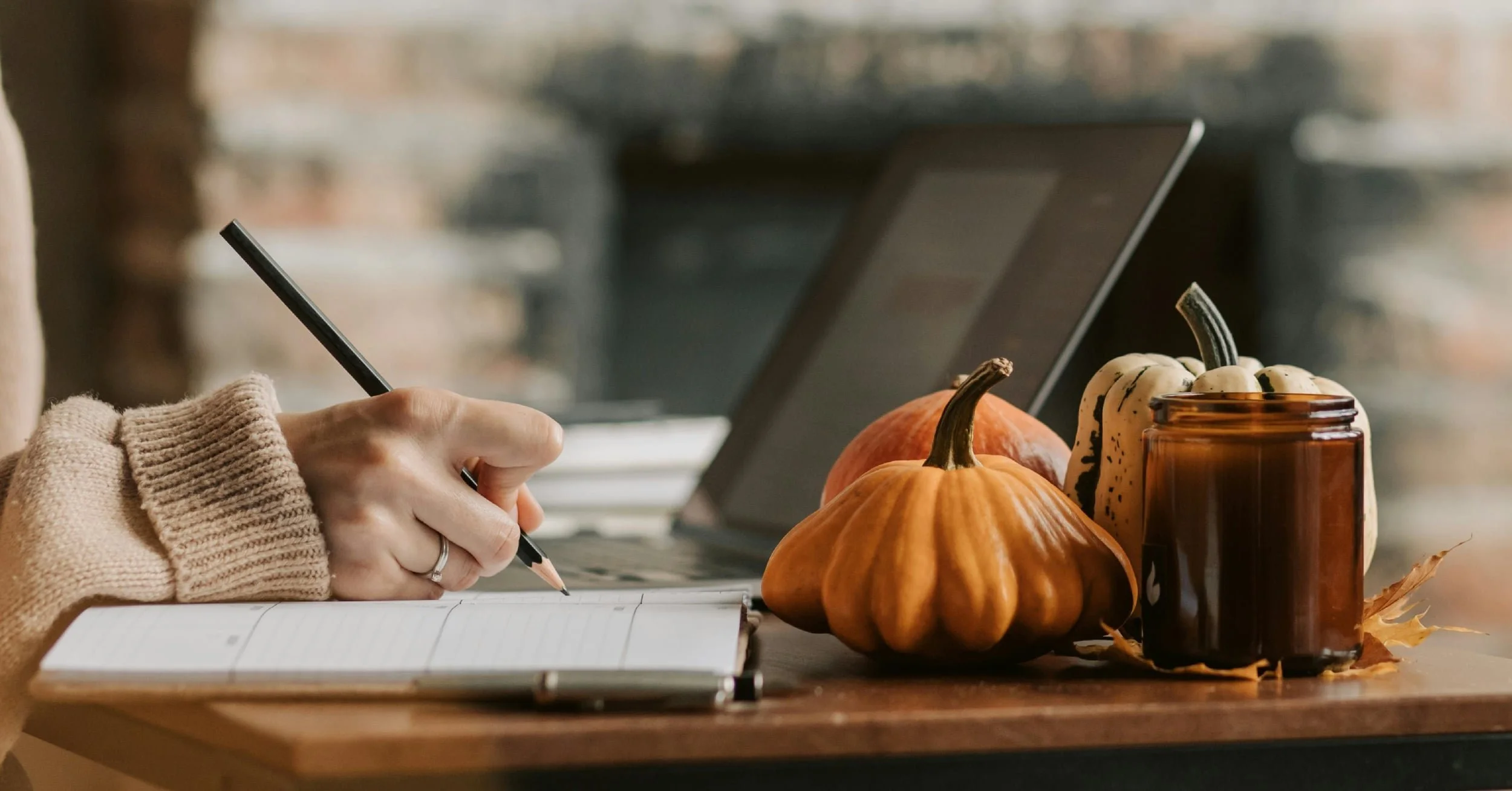 A woman working at a desk with pumpkins during the fall season.