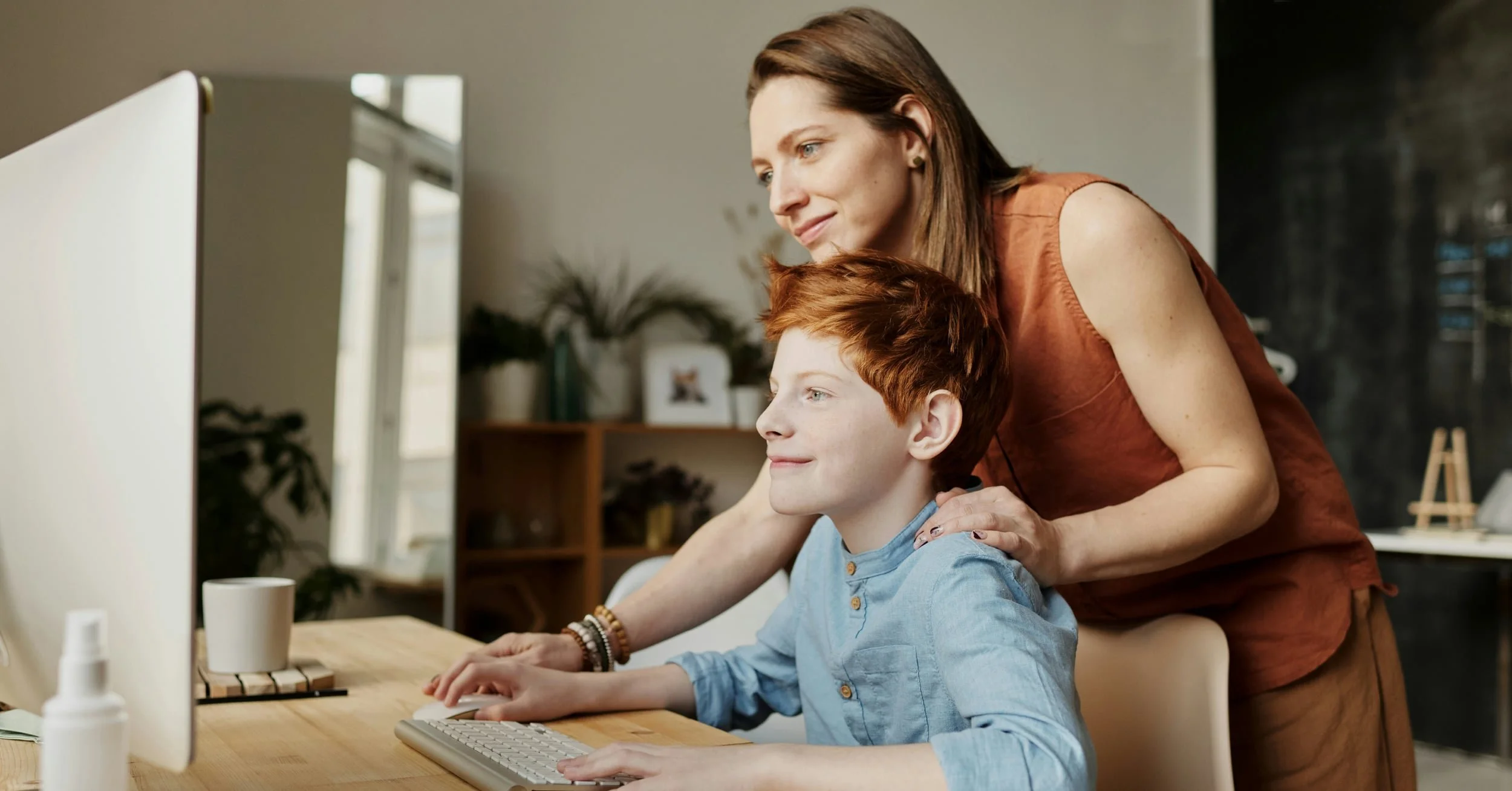 mother looking at computer over son's shoulder