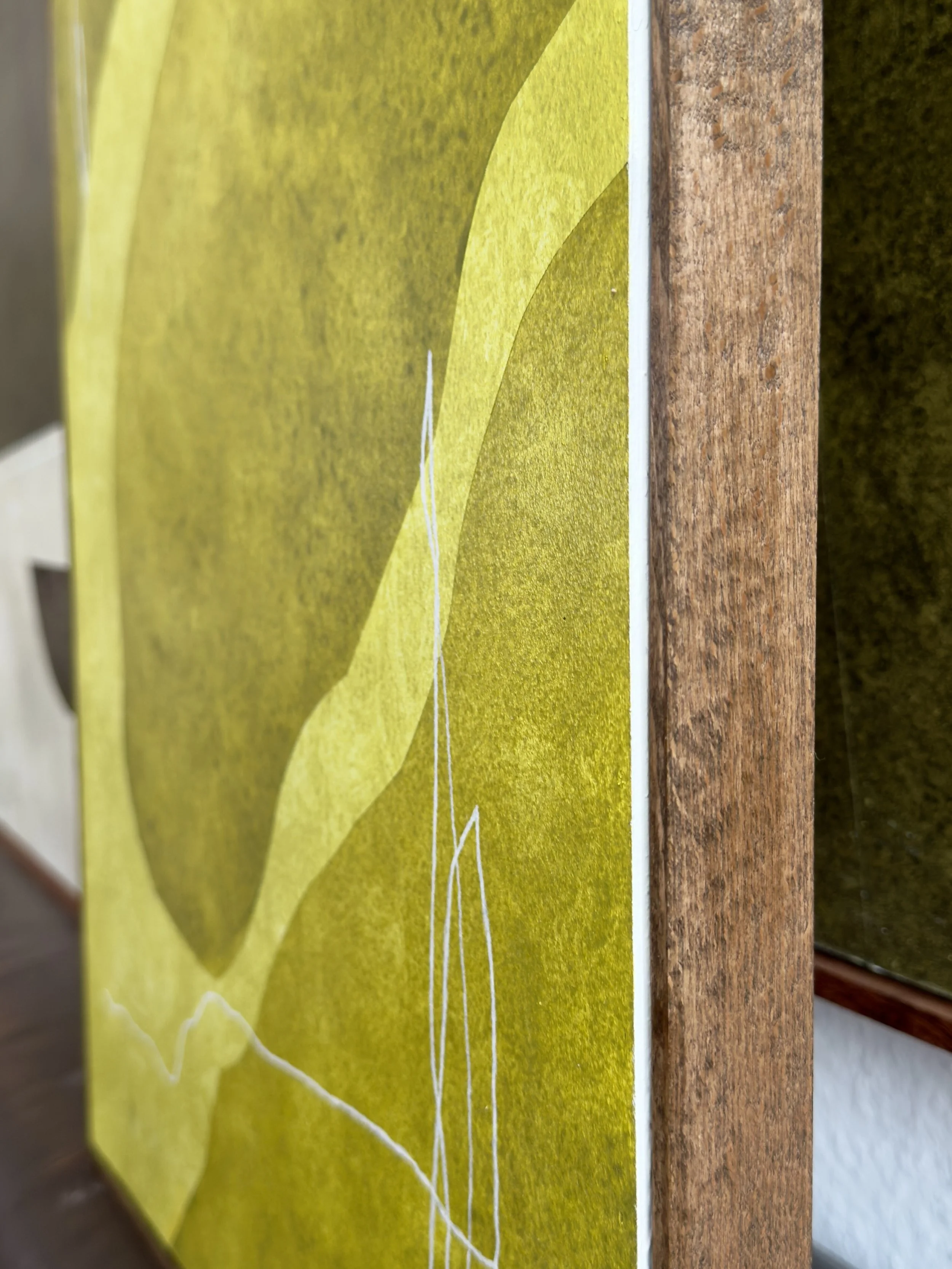 Nahaufnahme eines gelben und grünen Wandbilds, das auf einer Holzfläche montiert ist.