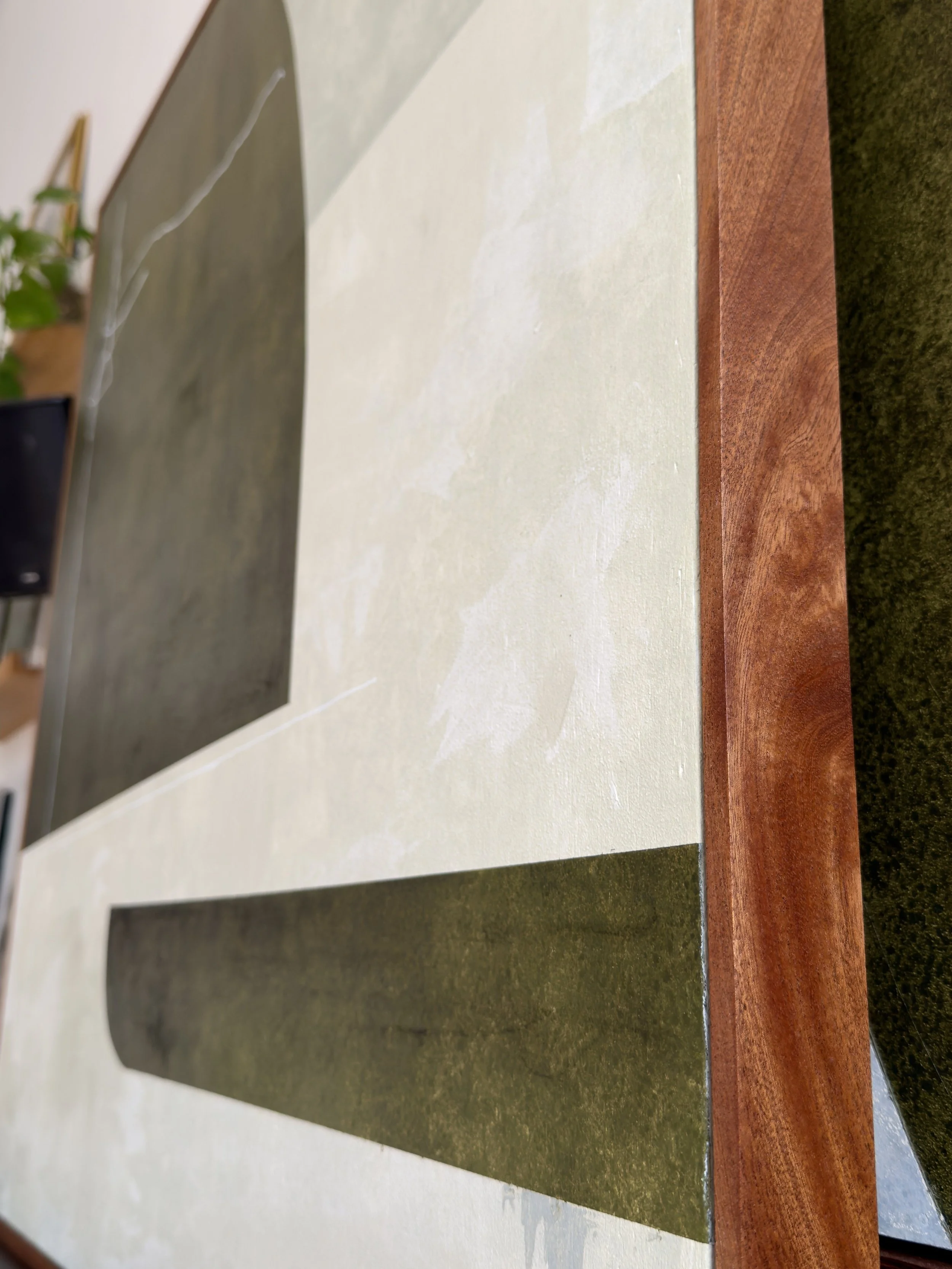 Ein Tisch mit mehreren rechteckigen, unterschiedlich farbigen Steinplatten in Beige, Dunkelgrün, Schwarz und Holzfarben. Dahinter ist ein Teil eines Raums zu sehen mit Pflanzen und Möbeln.