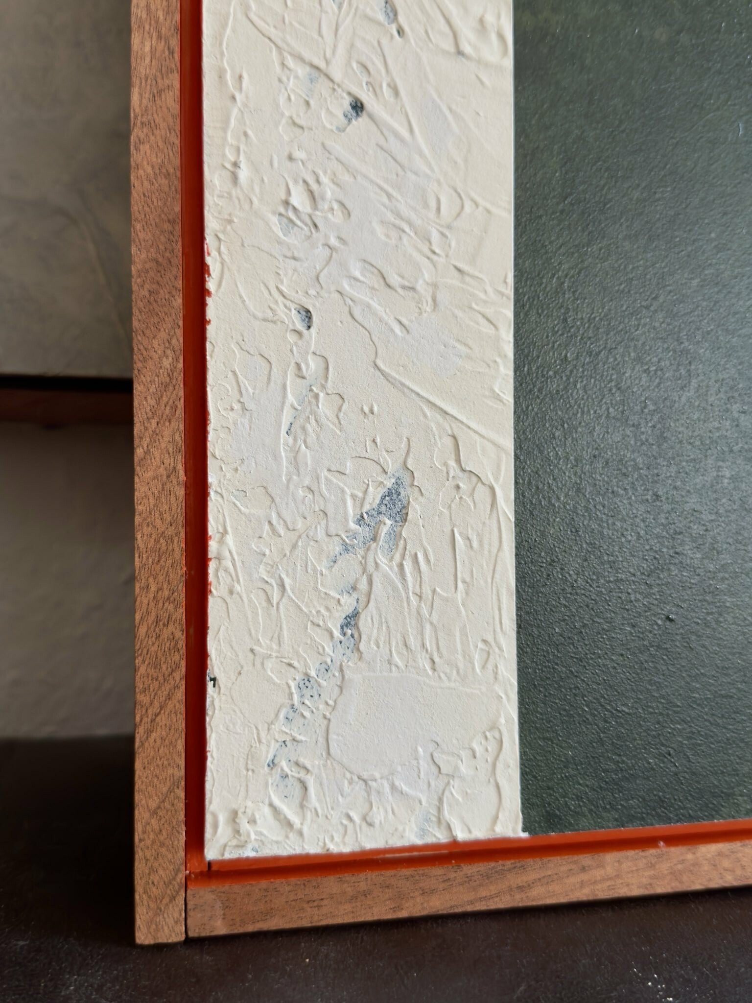 Strukturiertes, abstraktes Acrylgemälde mit einem großflächigen grünen Farbfeld. Ein hervorstechendes orangenes Element setzt einen starken farblichen Akzent. Ergänzt wird das Werk durch weiße Strichlinien und Gipsformen, die zusätzliche Tiefe und Ma