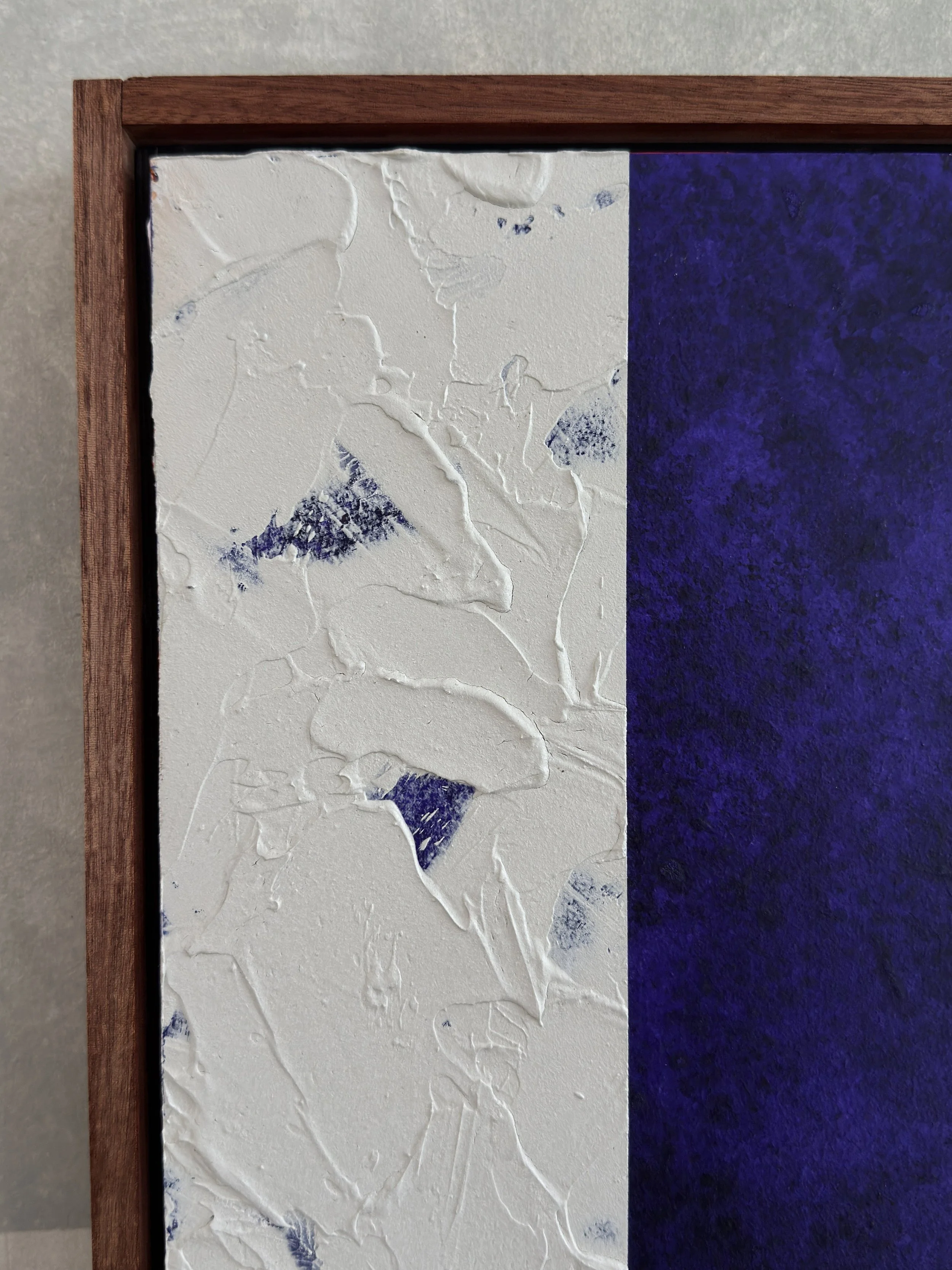 Abstrakte Kunst mit weißer Oberfläche, Texturen und blauen Akzenten, in einem Holzrahmen.