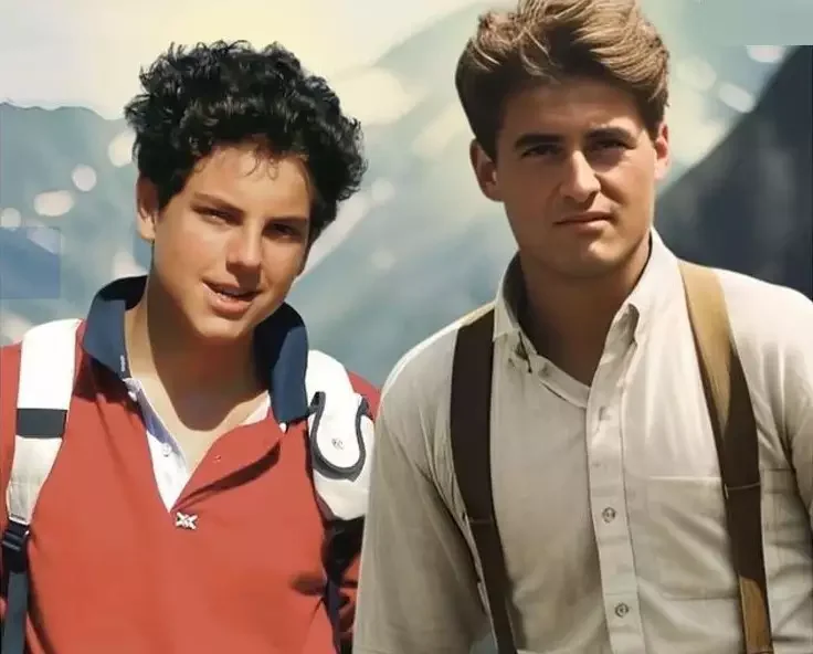 Two young men hiking outdoors with mountainous background, wearing casual clothes and carrying backpacks.