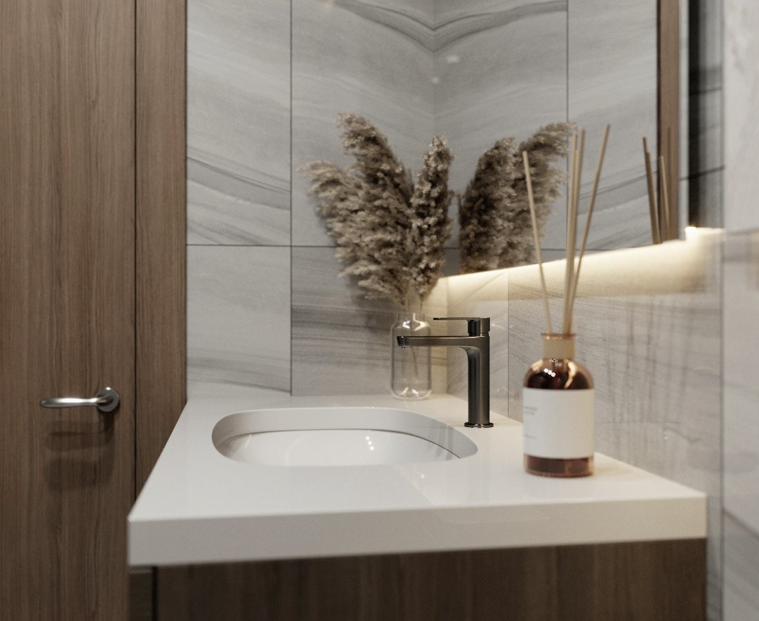 Modern bathroom vanity with a white sink, black faucet, glass with pampas grass, and reed diffusers, against a background of gray marble tiles.