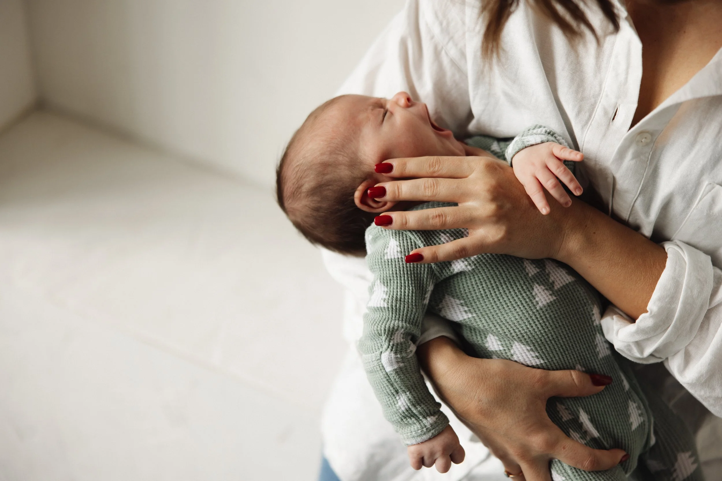 A woman holding a yawning baby in her arms indoors doing CFT on infant