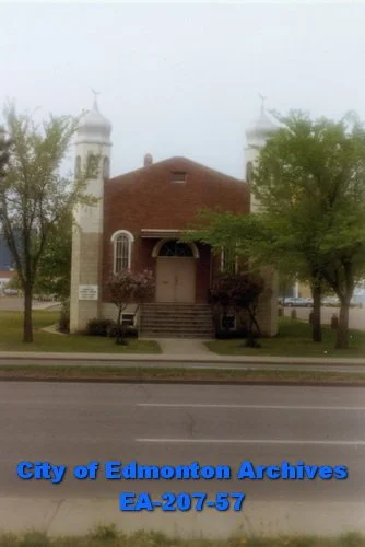 A small rectangle brick building with two white towers on either side.