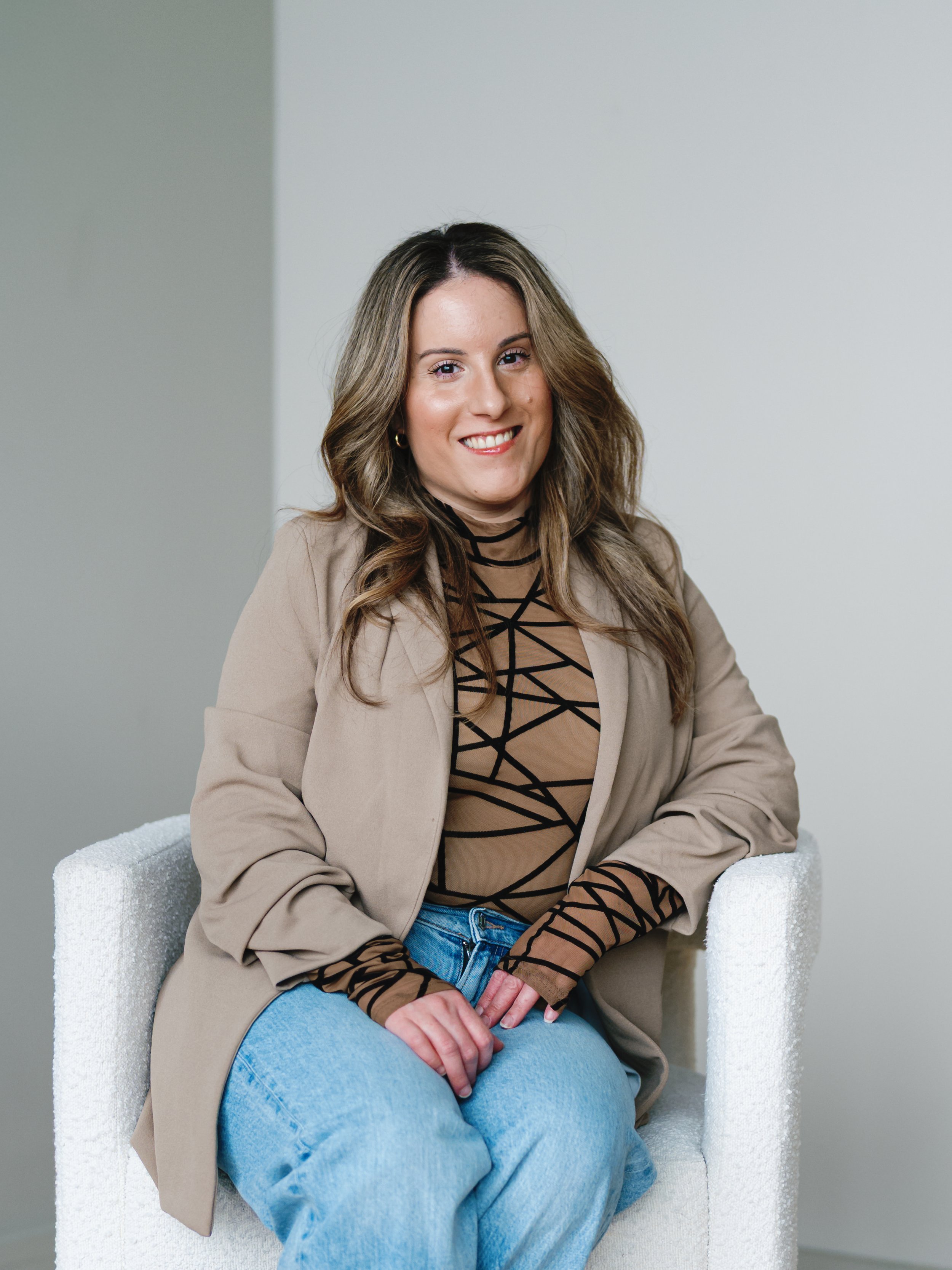 Black and white photo of a smiling woman with curly hair, wearing a white top and black leather jacket.