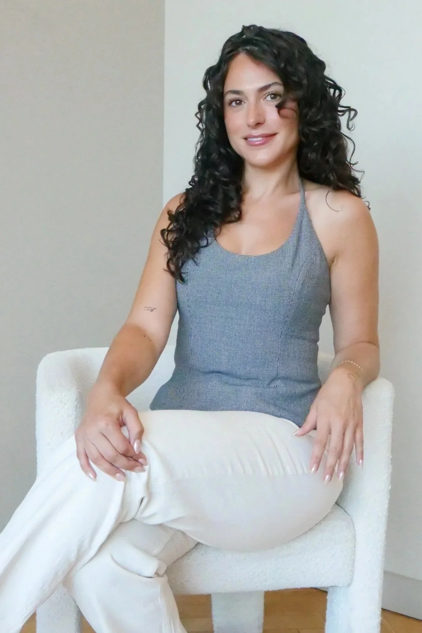 A black-and-white portrait of a woman with shoulder-length dark hair, wearing a black top and a delicate necklace, smiling slightly against a plain white background.