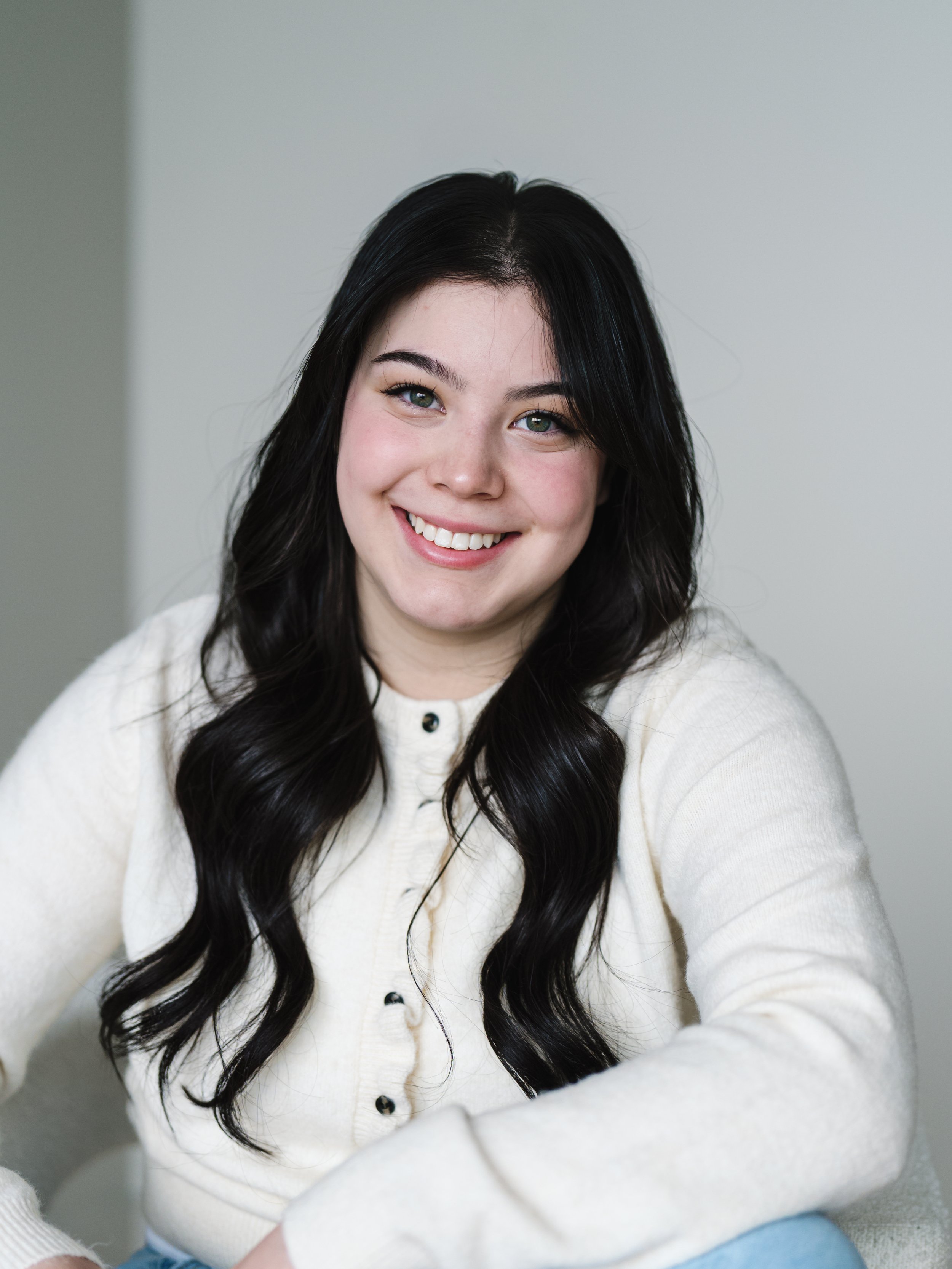 Black and white portrait of a young woman with straight, shoulder-length dark hair, wearing a black top, against a white background.