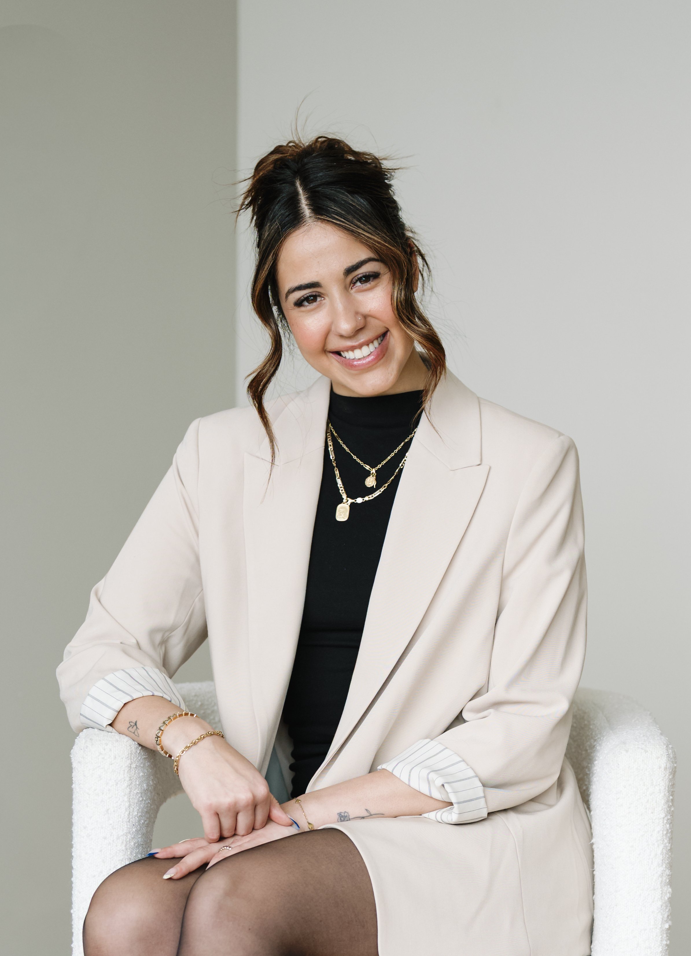 Black and white portrait of a young woman with long dark hair, smiling, wearing a short sleeve top and layered necklaces.