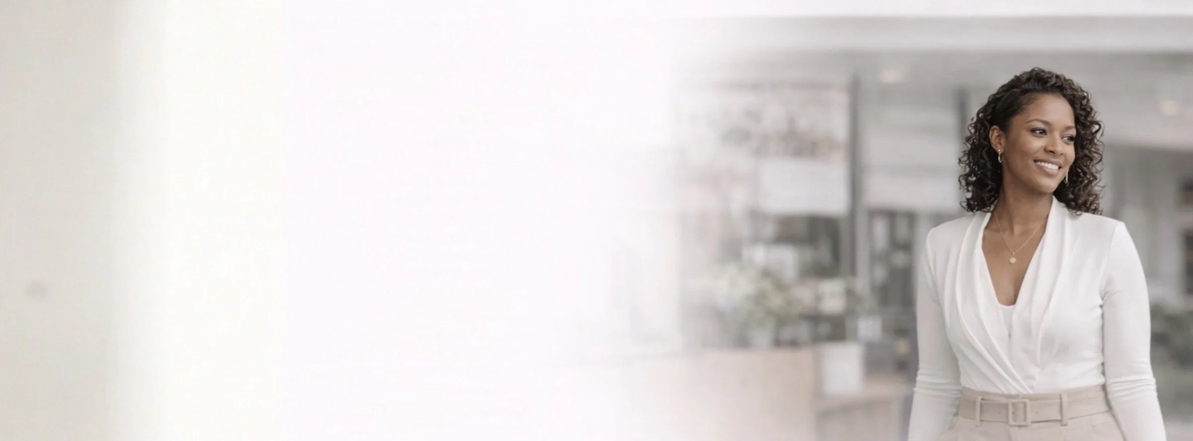 A smiling woman in business attire standing in an urban office setting.