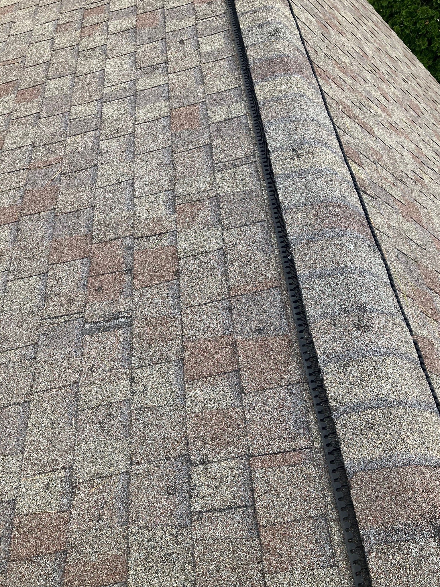Close-up of a section of a shingled roof with black roofing underlayment strips showing along the ridge.