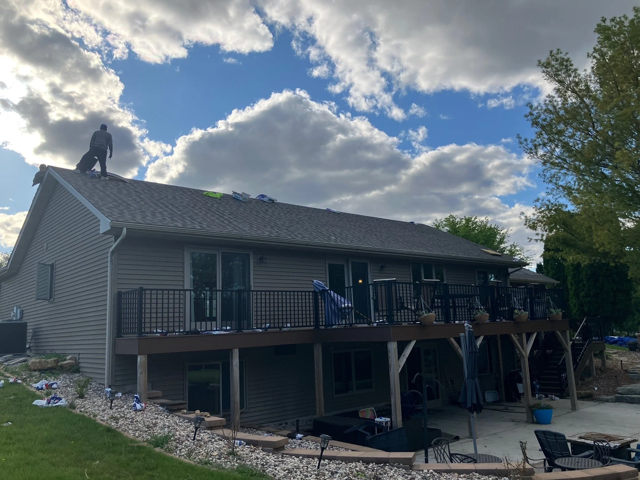 People working on the roof of a house during the daytime with scattered clouds in the sky