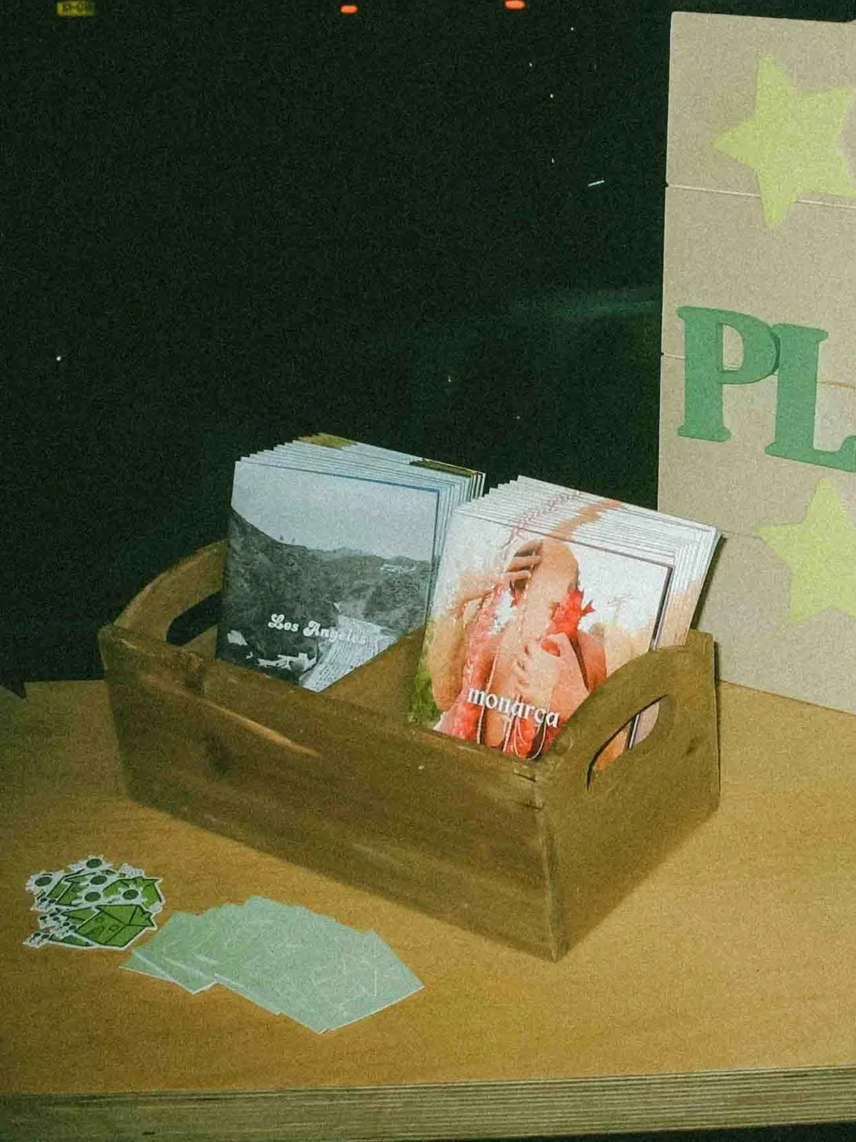The Los Angeles and Monarca zines on a wooden tray, with additional Pluto's stickers.