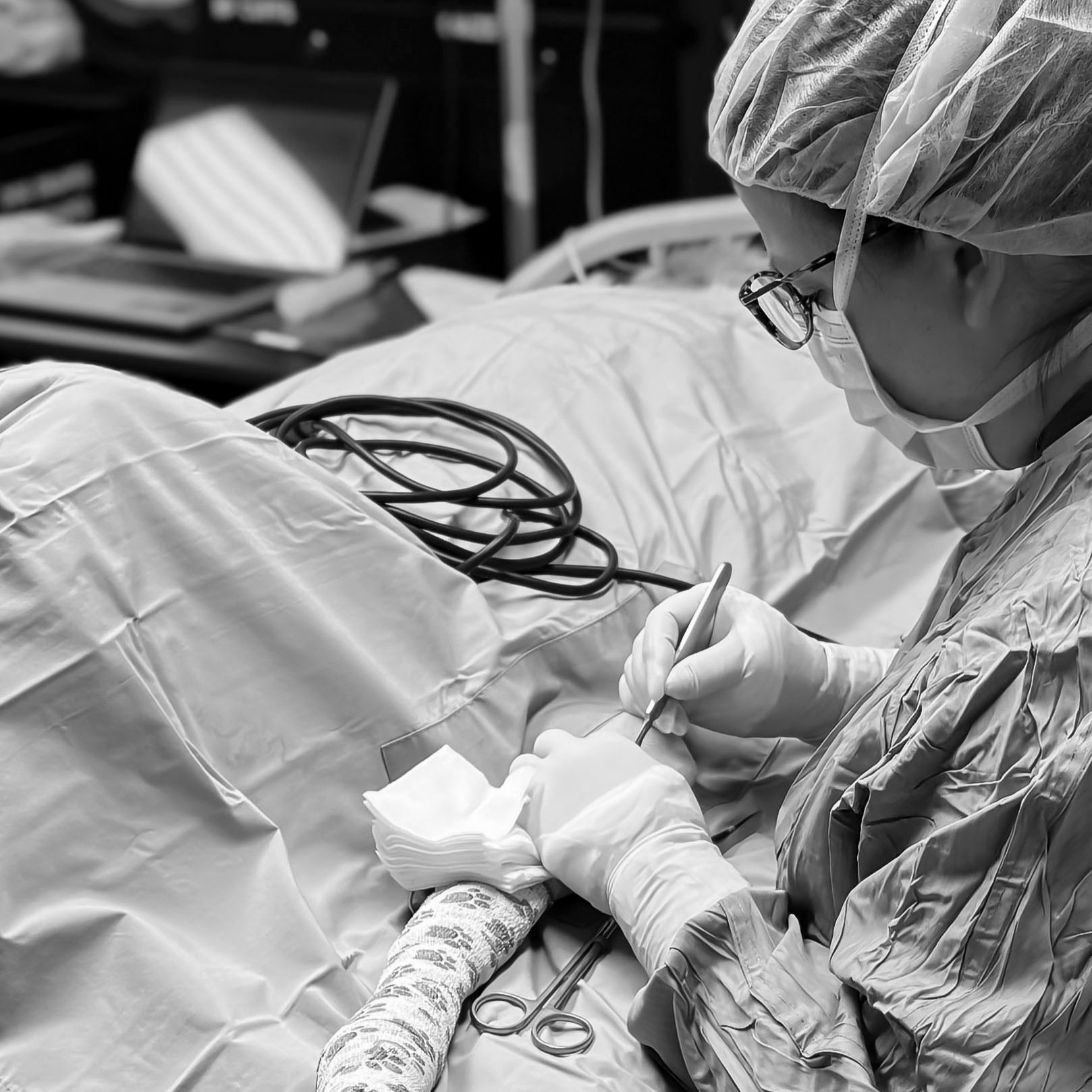 A healthcare professional in protective gear performing a procedure in a hospital setting.