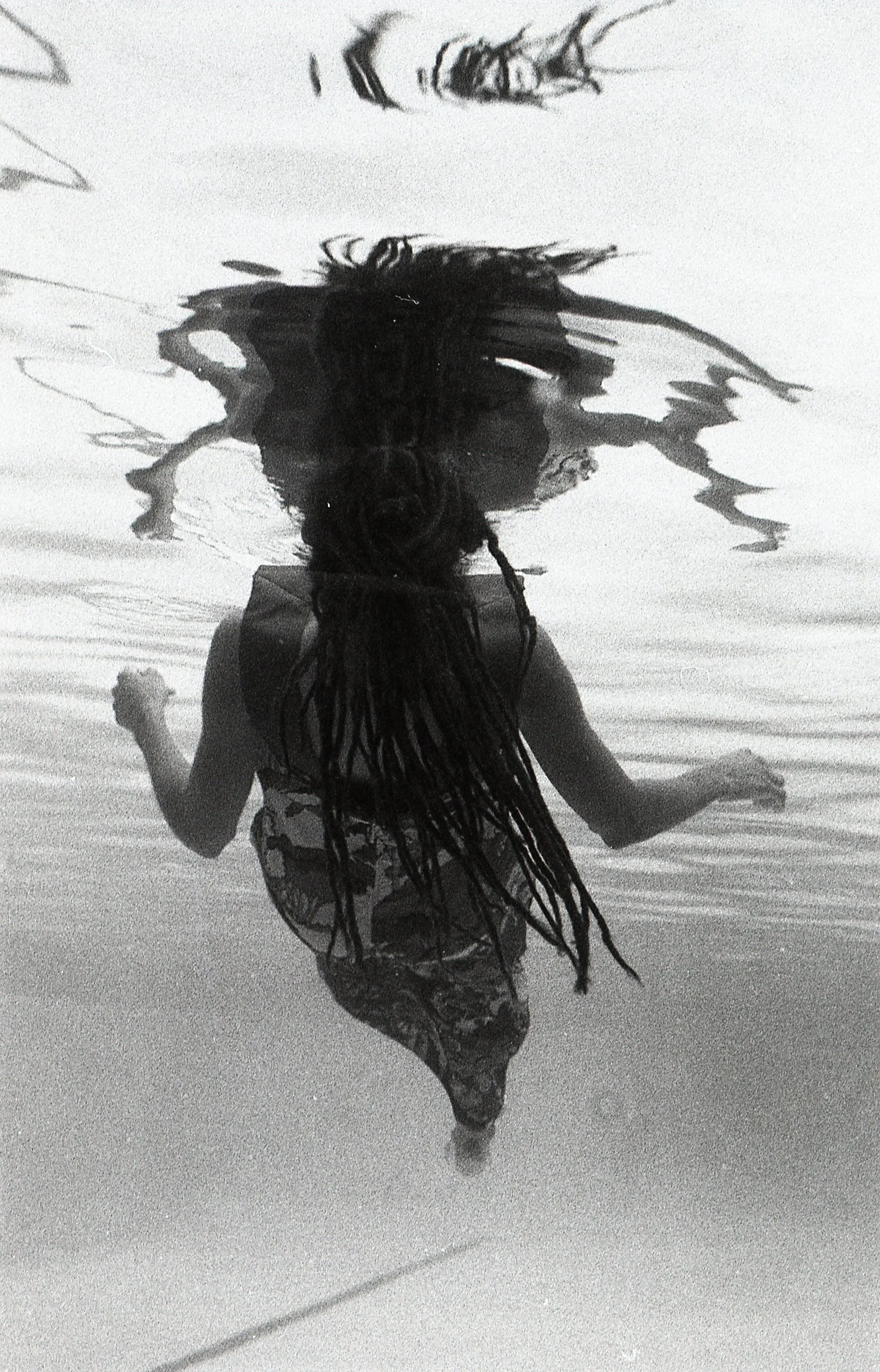 An vantage point underneath a woman that is floating in a pool.