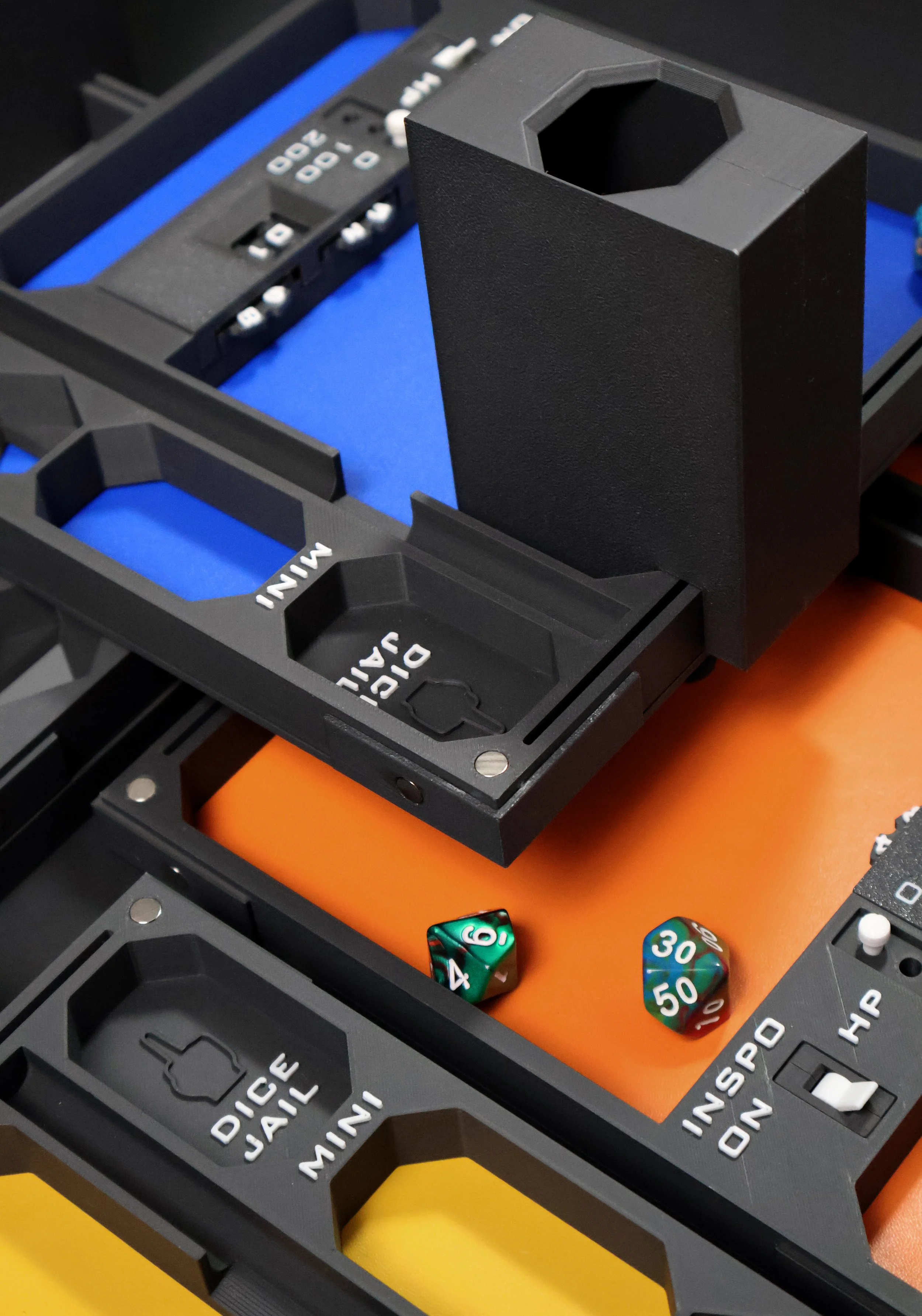 Close-up of from the dice tower game setup, showing colorful polyhedral dice, and parts of game components with various markings and colors.