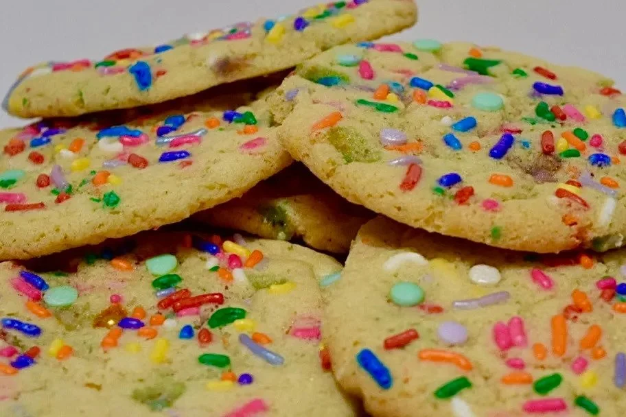 Close-up of colorful sprinkled sugar cookies stacked on top of each other.