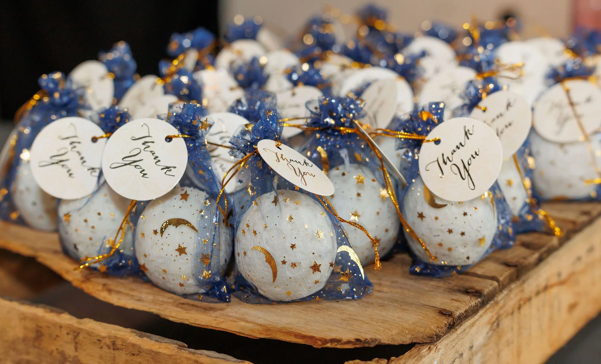 Small fabric pouches decorated with moon and star patterns, tied with blue mesh and gold ribbons, with 