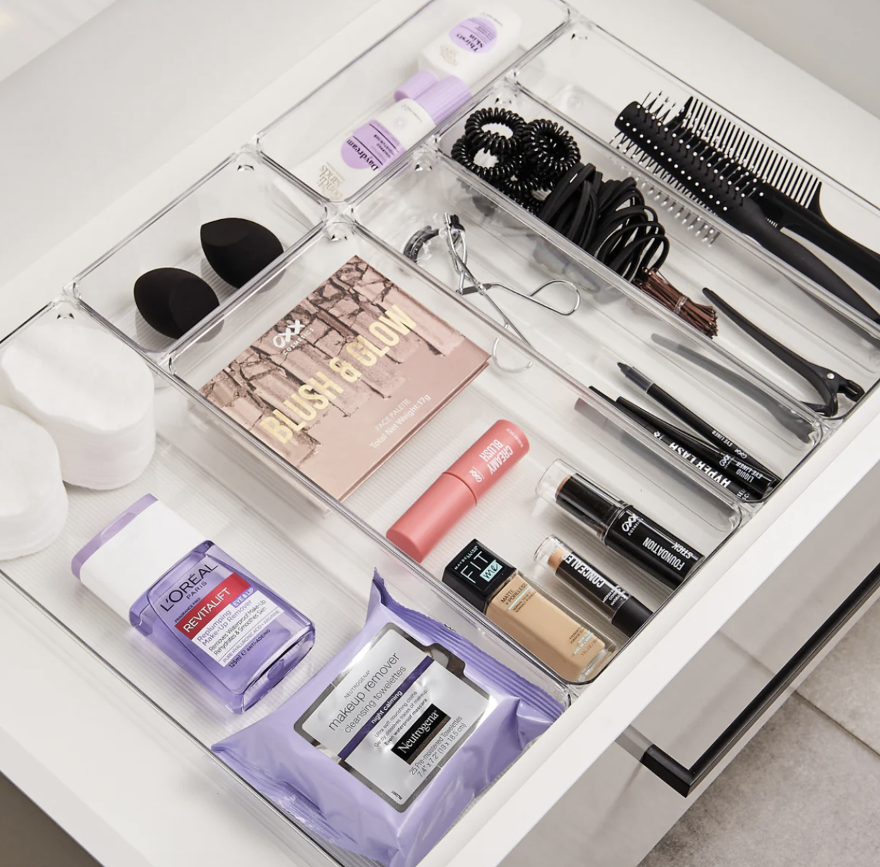 Organized makeup drawer with skincare, brushes, eyeliners, lipstick, and makeup sponges.