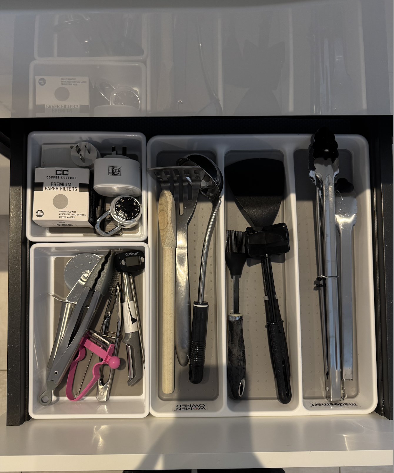 Drawer with various kitchen tools including tongs, ladle, spatula, meat mallet, and grilling accessories.