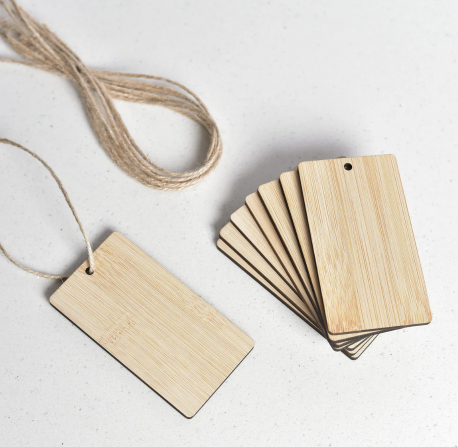Blank wooden cards with a string attached, and a stack of similar cards on a white surface.