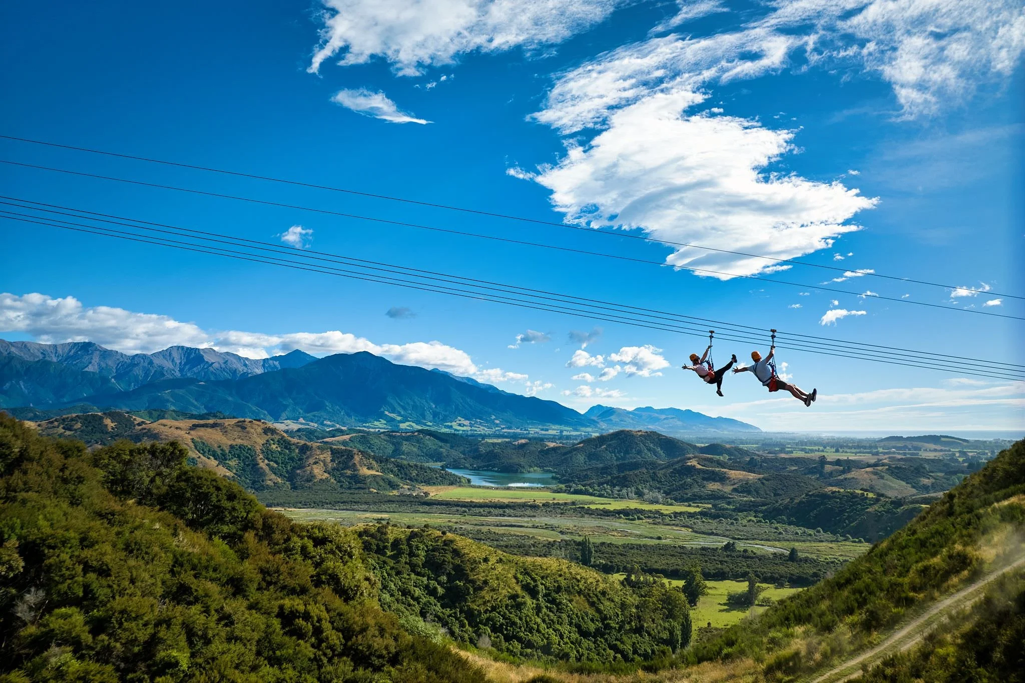 Two people on a zipline with epic Kaikoura views in the background