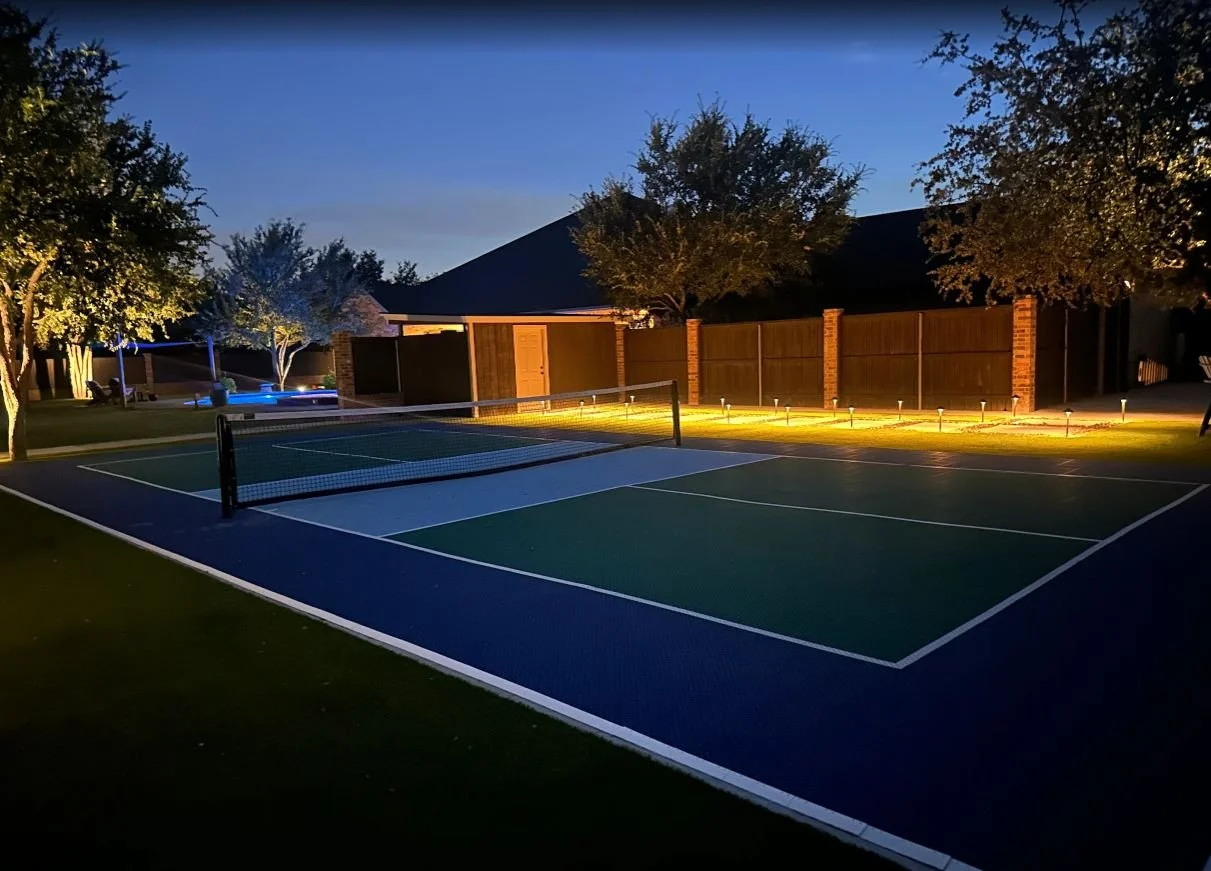 Nighttime pickleball court with integrated synthetic turf and professional landscape lighting design in Midland, TX