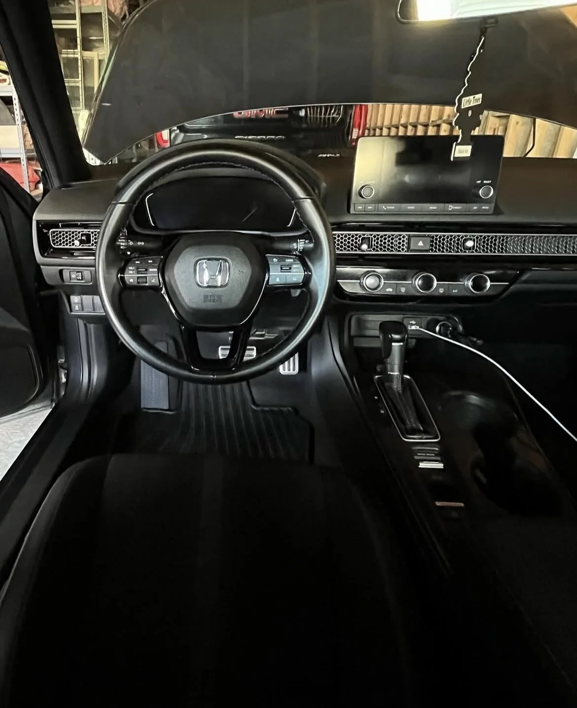 Interior of a Honda vehicle showing the steering wheel, dashboard, gear shift, and a digital display screen.