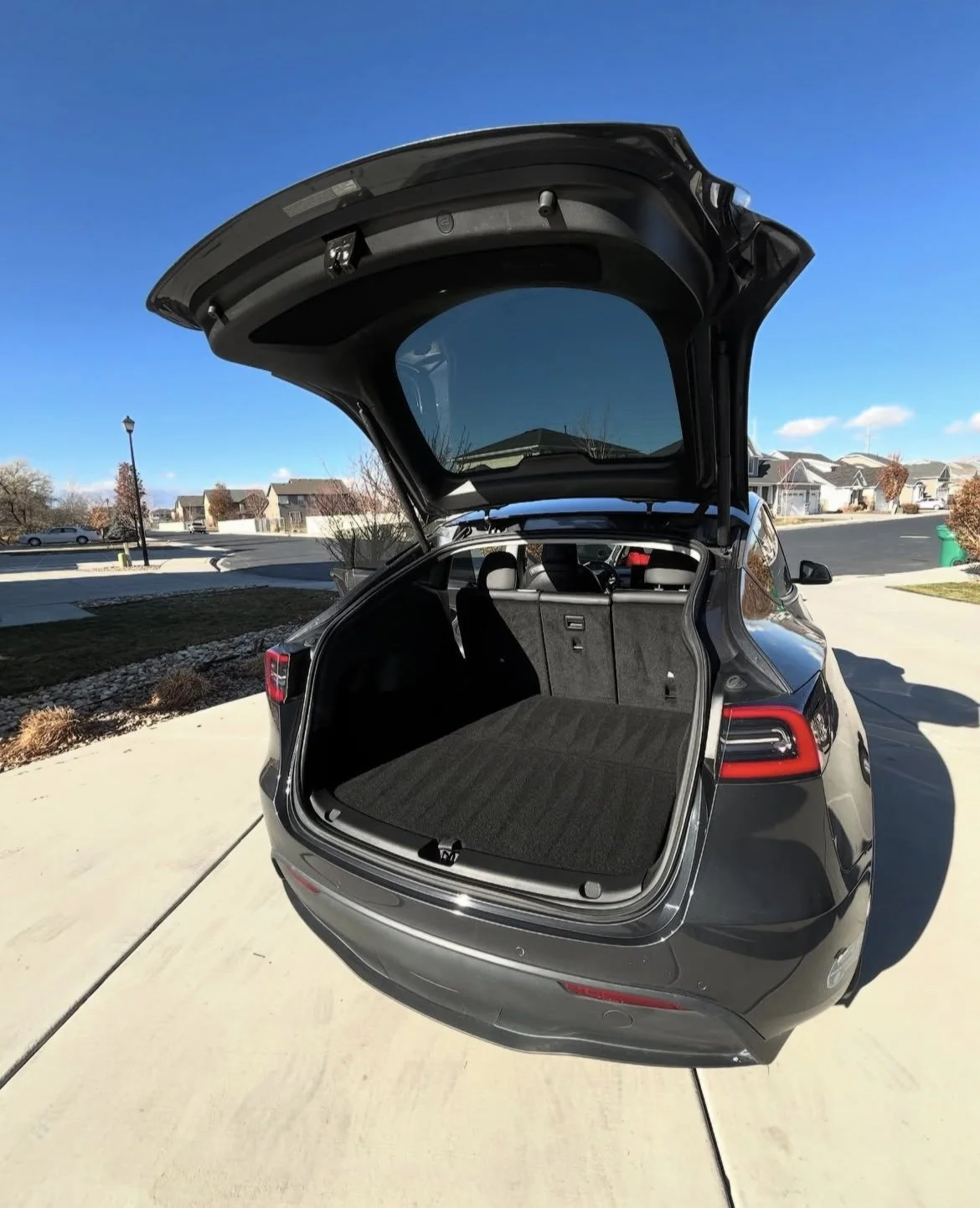 Open trunk of a black SUV parked in a residential neighborhood on a sunny day.