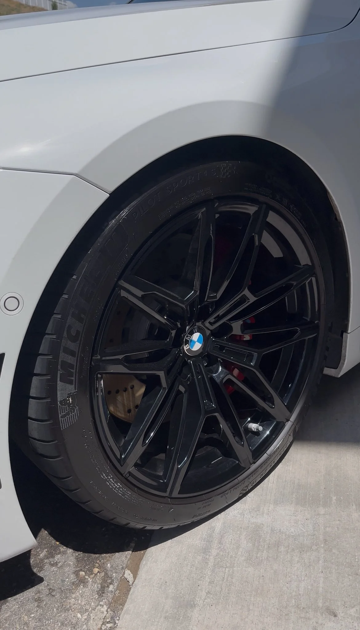 Close-up of a black, multi-spoke BMW wheel with a tire mounted on a silver sports car.