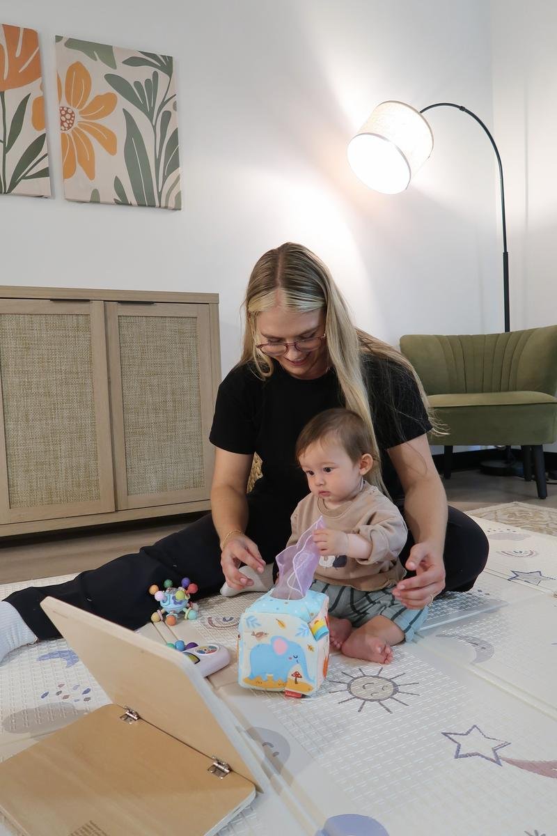 Pediatric physical therapist using play-based activities to support a baby's motor milestones during an in-home visit in Costa Mesa, CA.
