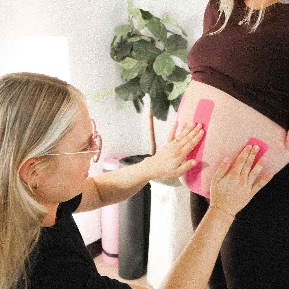 Dr. Avonlea Brown applying kinesiology tape to a pregnant client's belly — Avonlea Brown Physical Therapy, Costa Mesa, CA.
