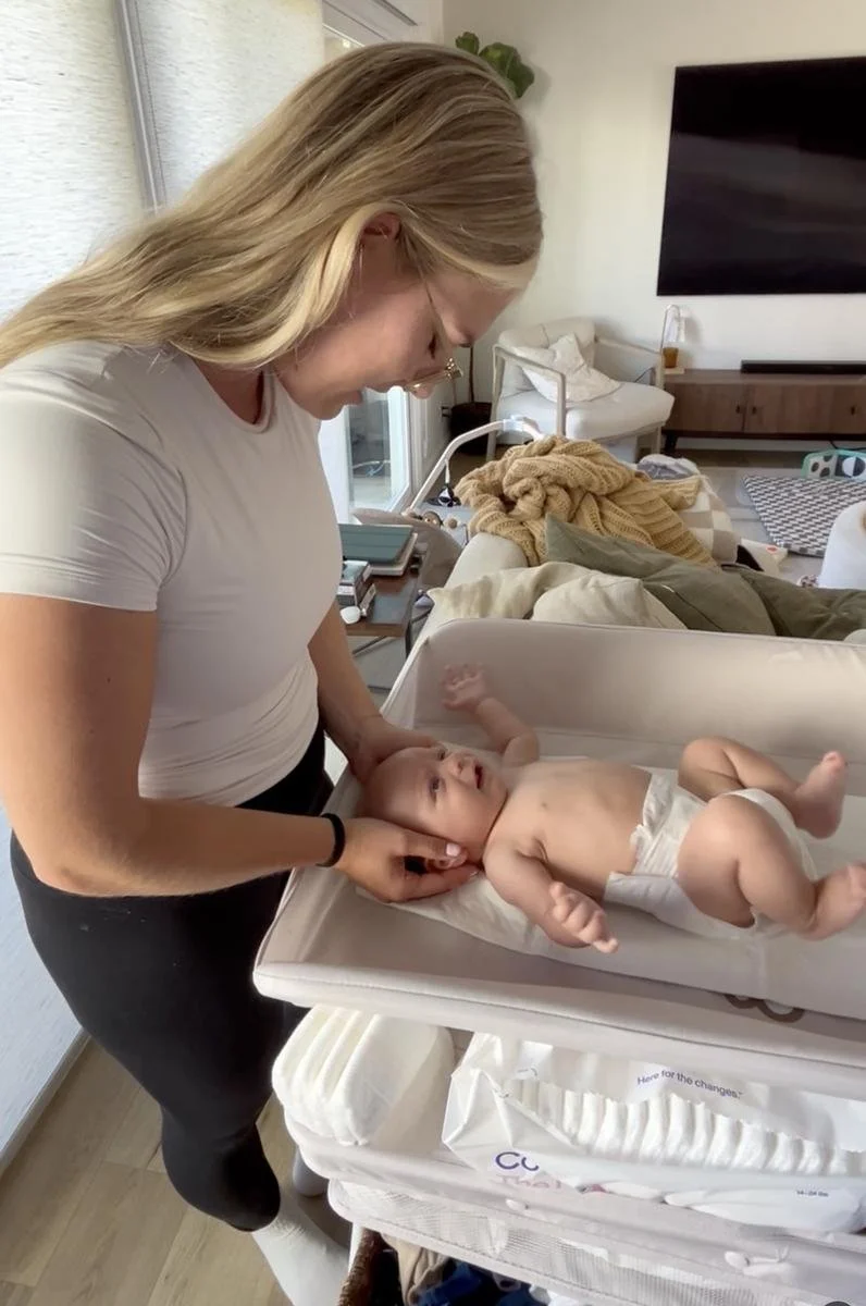 Pediatric physical therapist assessing a baby's head and neck control during an in-home motor milestone evaluation in Costa Mesa, CA.