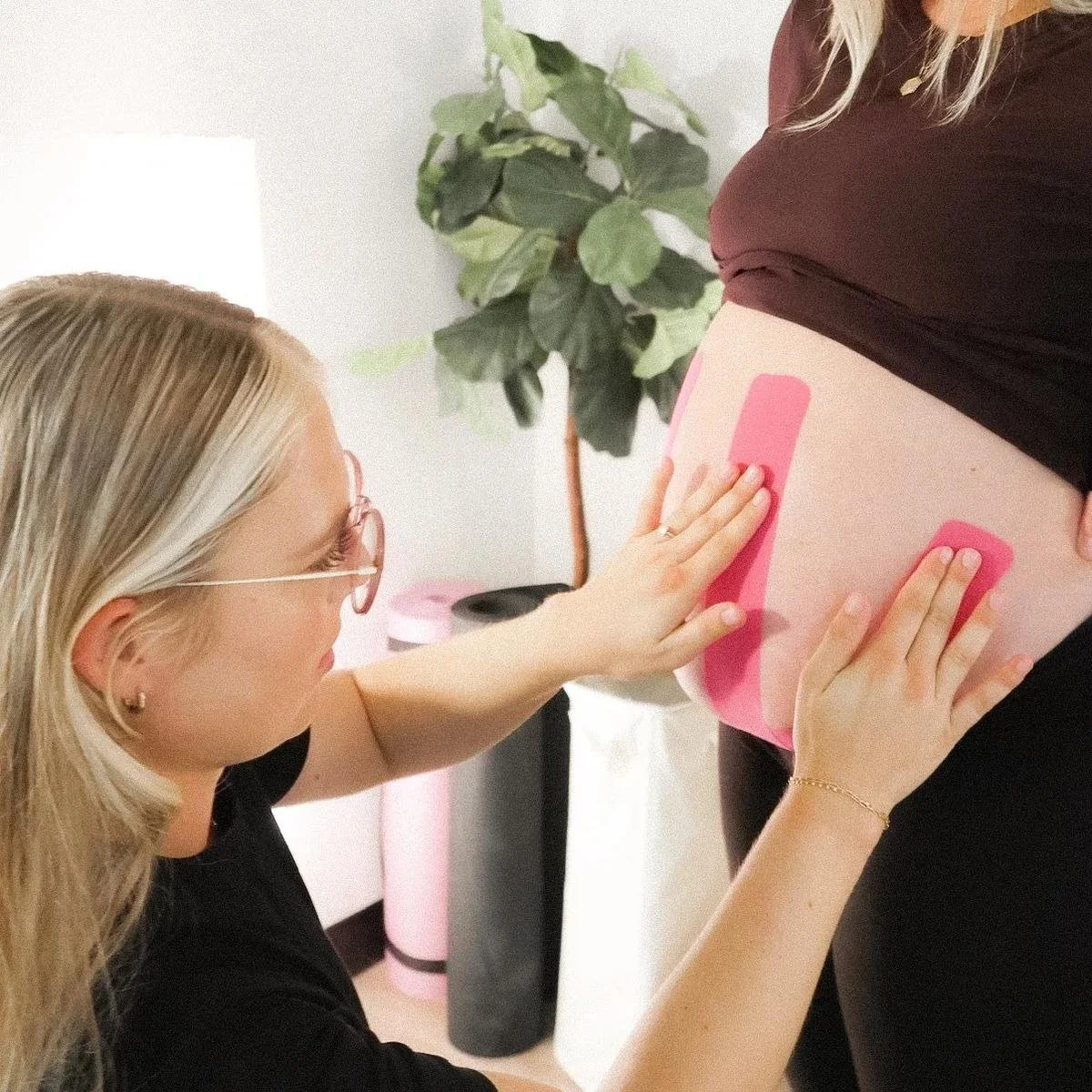 Dr. Avonlea Brown applying kinesiology tape to a pregnant client's belly — Avonlea Brown Physical Therapy, Costa Mesa, CA.