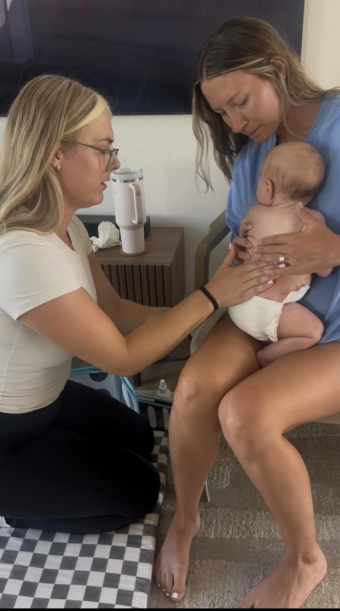 Pediatric physical therapist assessing a baby held by a parent during an in-home infant physical therapy visit in Costa Mesa, CA.