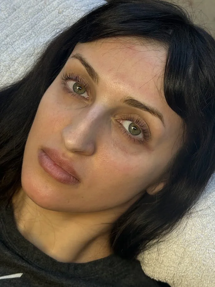A woman with dark hair and green eyes looking at the camera.