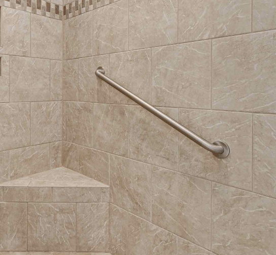 Interior of a shower with beige tiled walls and a stainless steel grab bar.