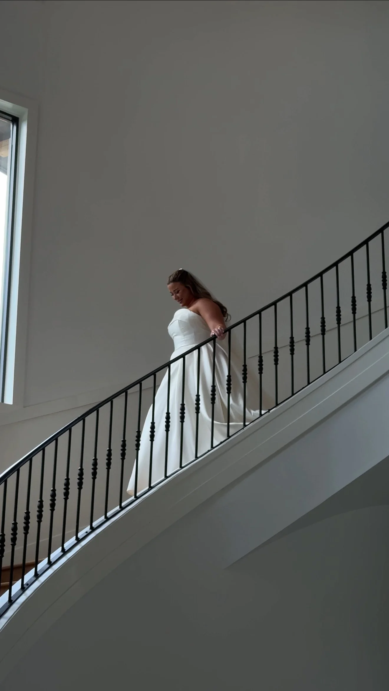 A woman in a white wedding dress walking down a staircase.