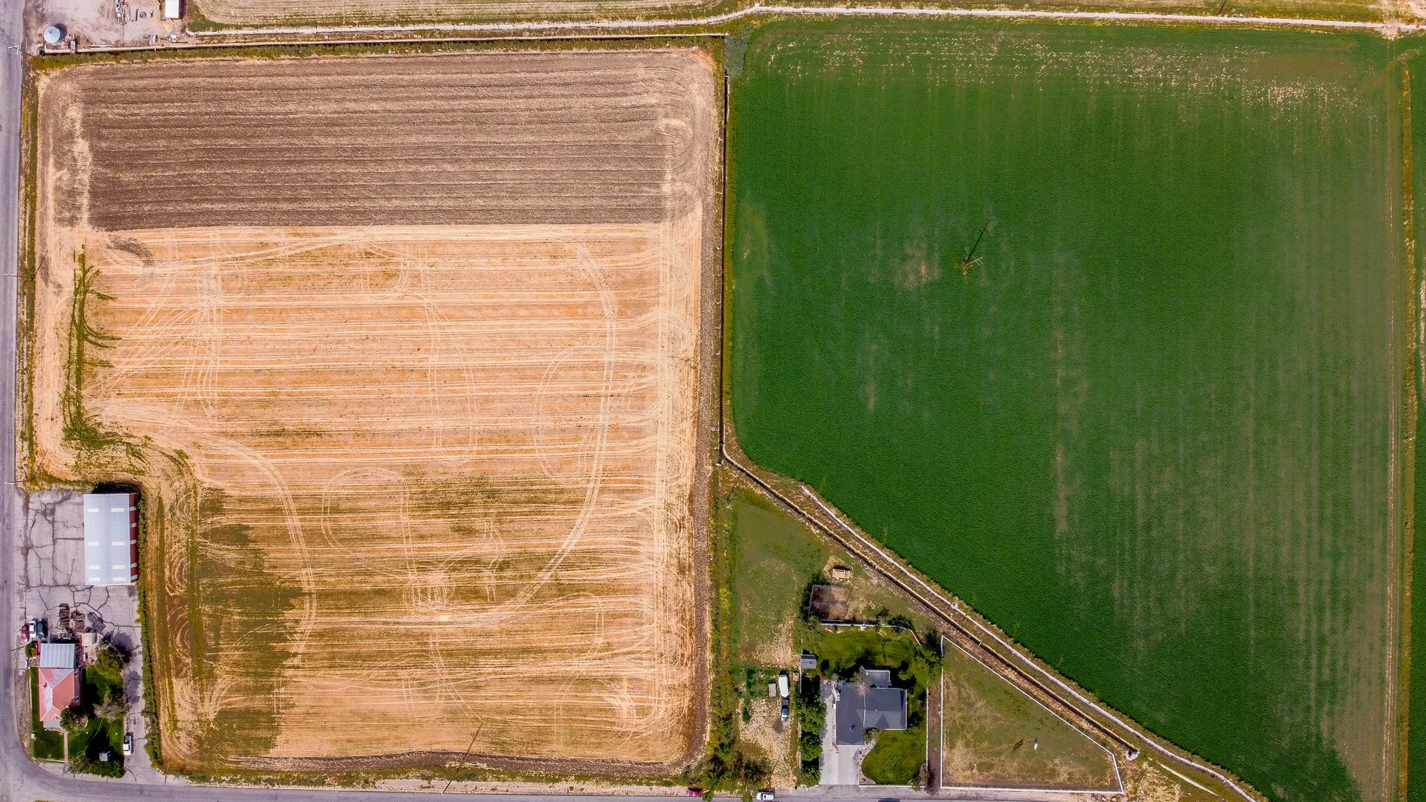 Aerial view of a backyard with a swimming pool, patio, green lawn, and neighboring houses.
