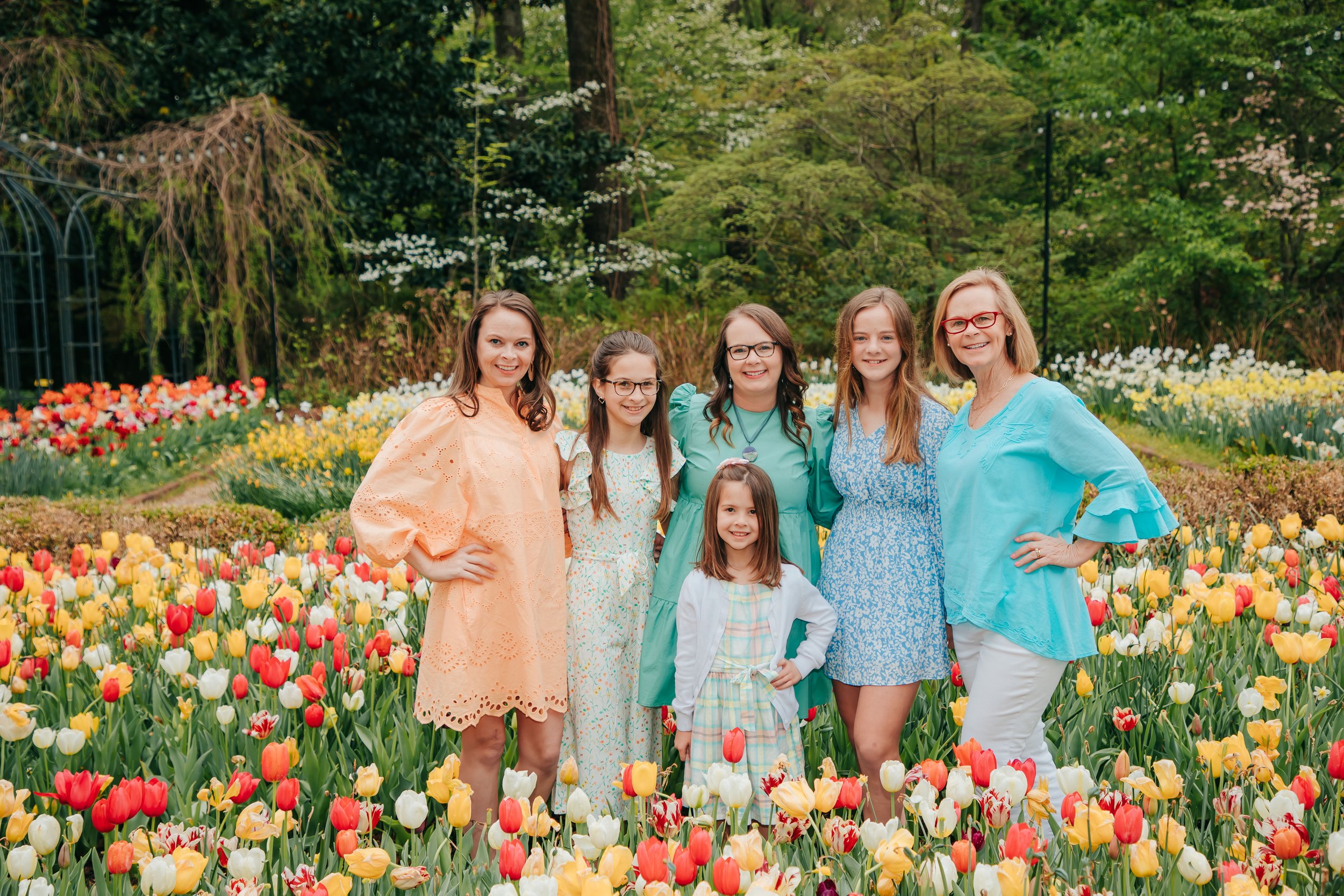 Six women and girls standing in a colorful tulip garden, smiling at the camera. Dixon Gallery. Memphis family photographer.