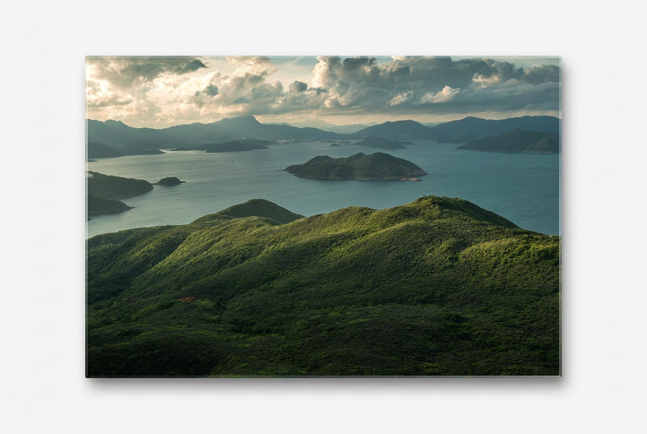 Serene coastal landscape of Clear Water Bay Country Park, Hong Kong — lush green rolling hills overlooking calm blue waters dotted with islands beneath a partly cloudy sky