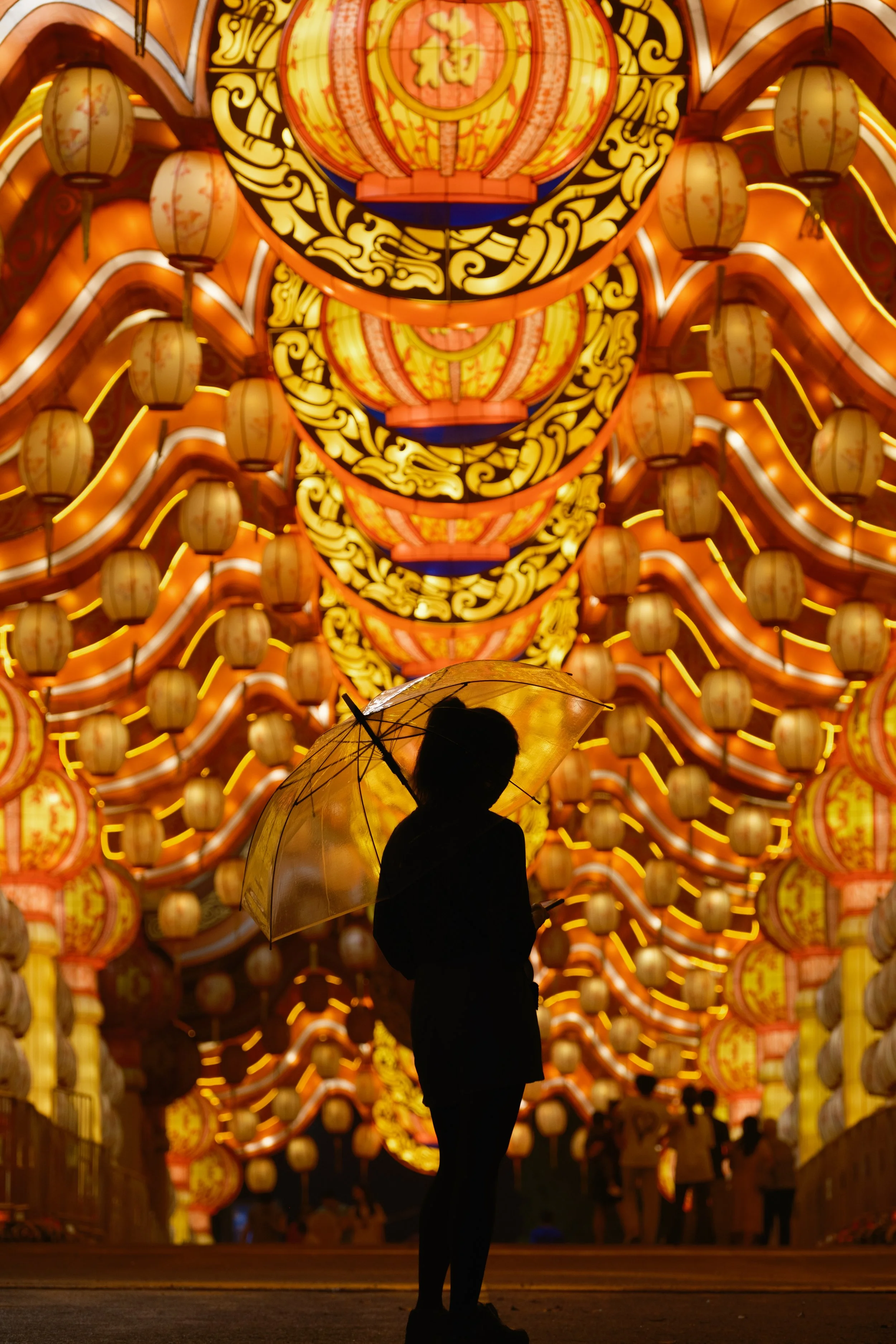 Enchanting Lanterns: A mysterious silhouette stands before towering lanterns during Chinese New Year, enveloped in dramatic festive light.