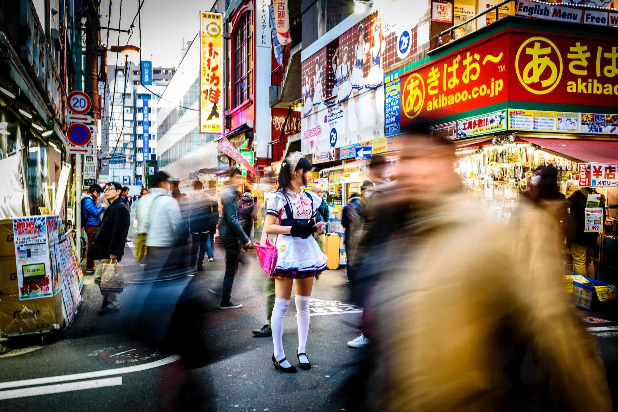 Street view of Akihabara, Tokyo with crowds and woman in maid outfit.