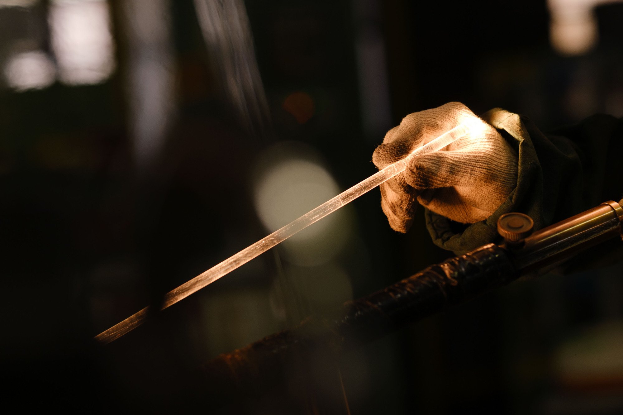Detail shot of handcrafted industrial glass glowing under workshop lighting.